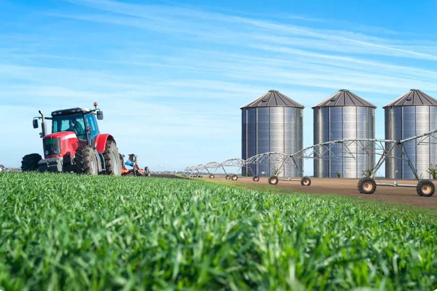 Tractor, storage silos and irrigation system beside a field